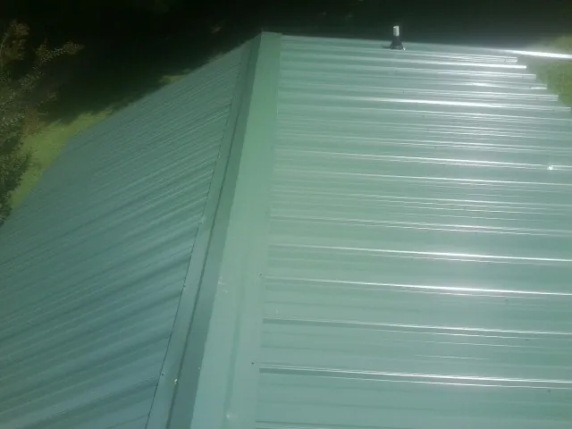 New green metal panels meeting at the ridge of a roof — Flat Roof Repair work by our crew in Goldvein