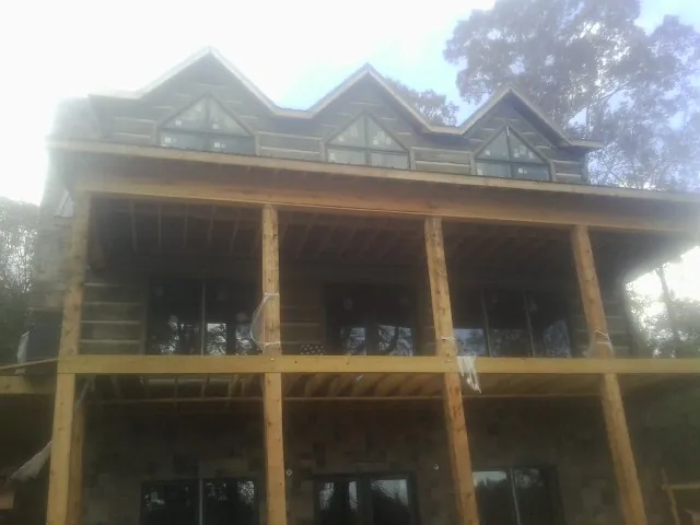 Dormers and porch framing on a large log home under construction — Roof Coating work by our crew in Goldvein