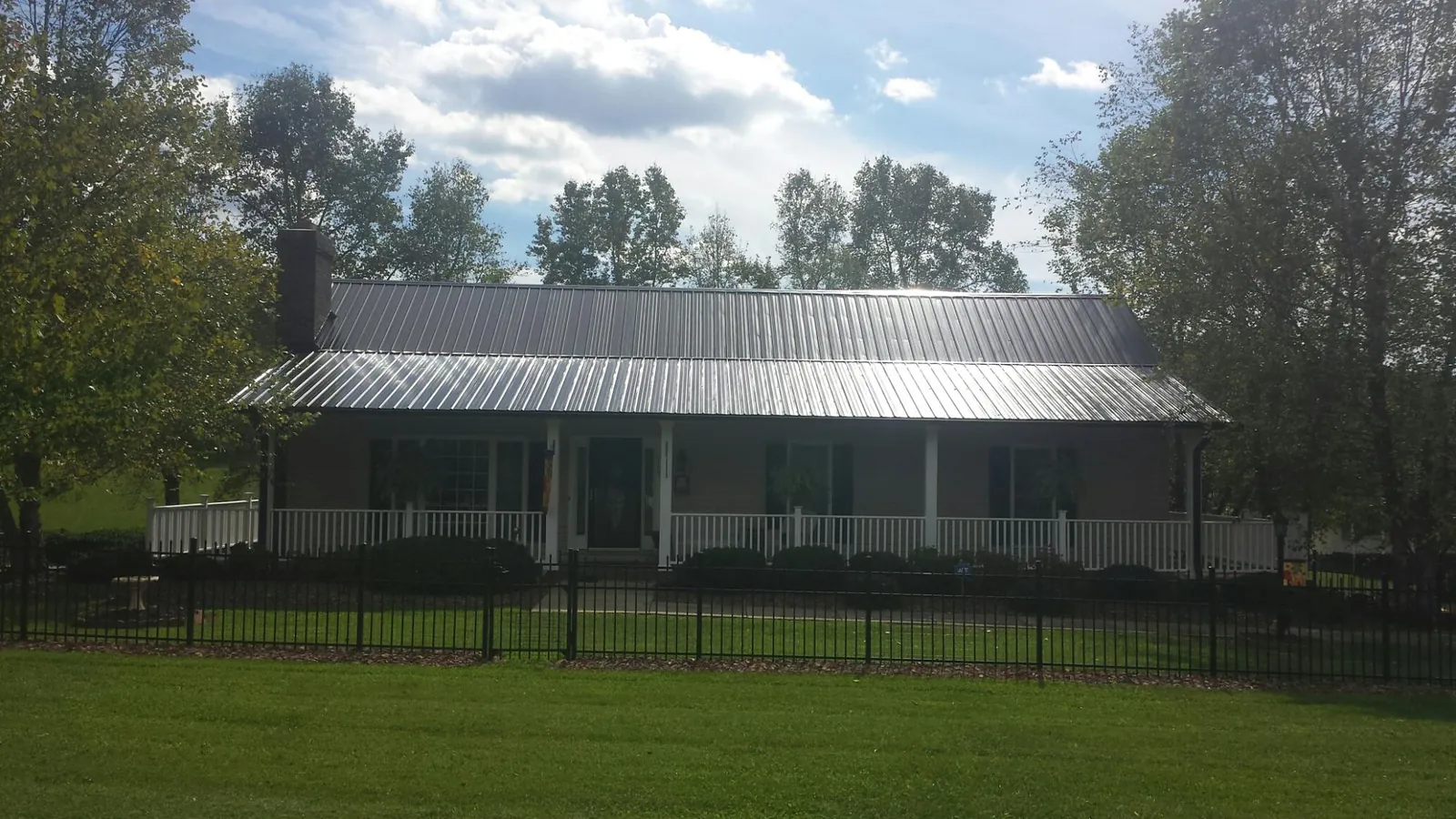 Gray metal roof on a brick ranch with a full width front porch — Gutter Guard Installation work by our crew in Goldvein