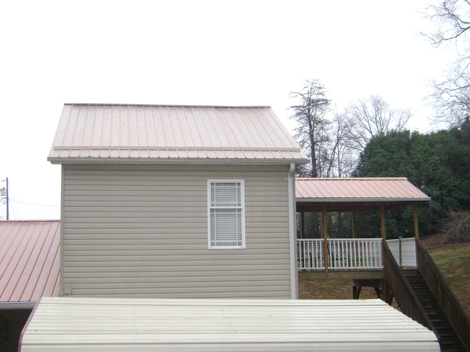 Tan metal roofs on a two story addition and attached porch, from a Roof Replacement job in Goldvein