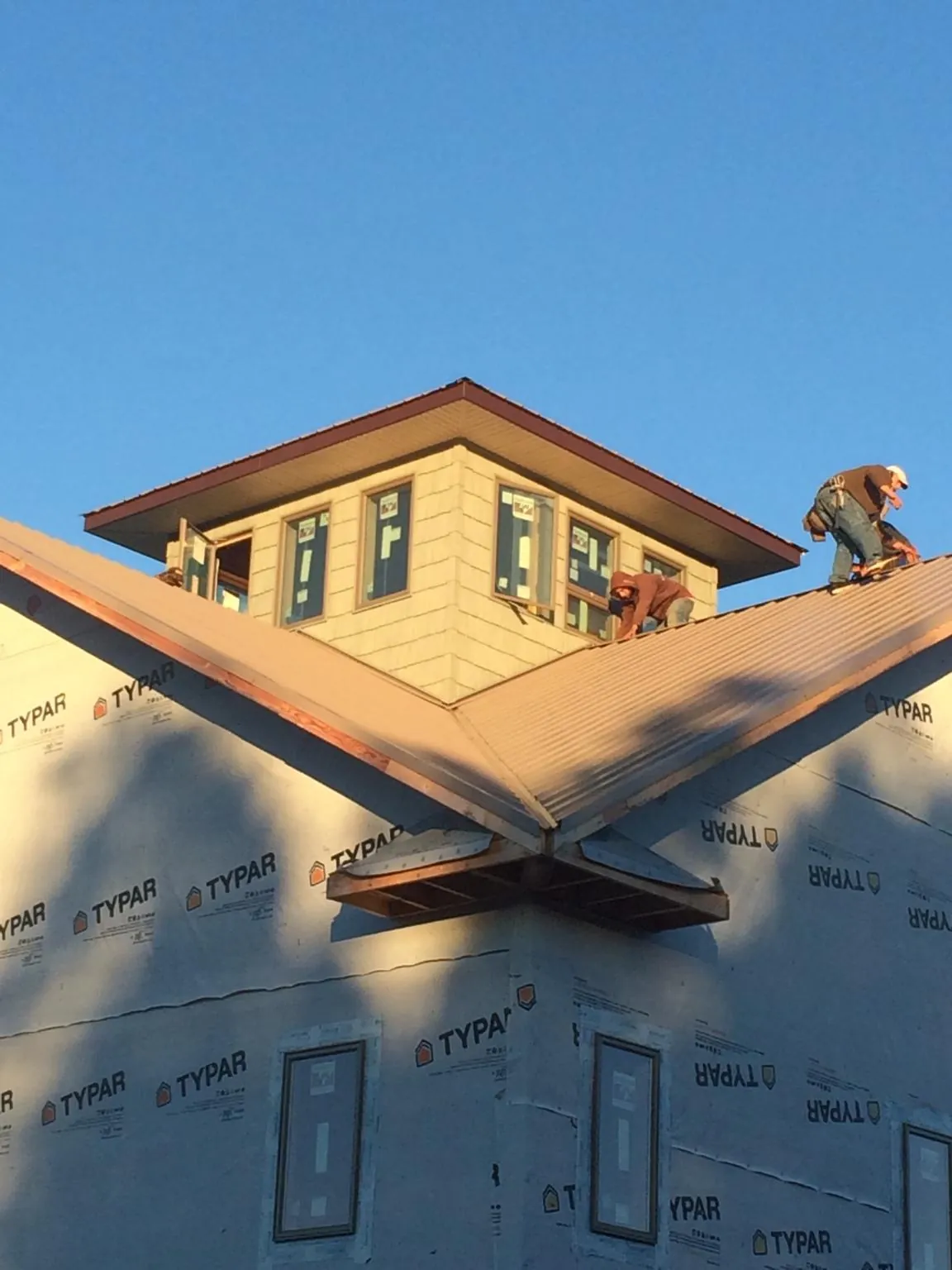 Roofers working around a rooftop cupola on a new metal roof at sunset — Roof Waterproofing in Goldvein by Roofing Brothers